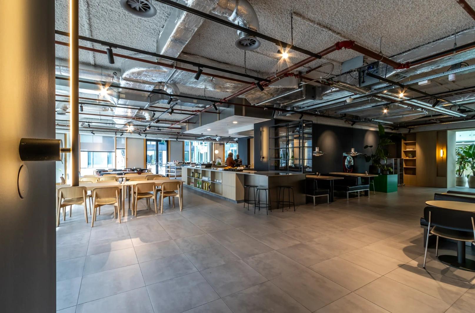 Modern office cafeteria at Pedro de Medinalaan with open seating, bar area, and industrial ceiling design.