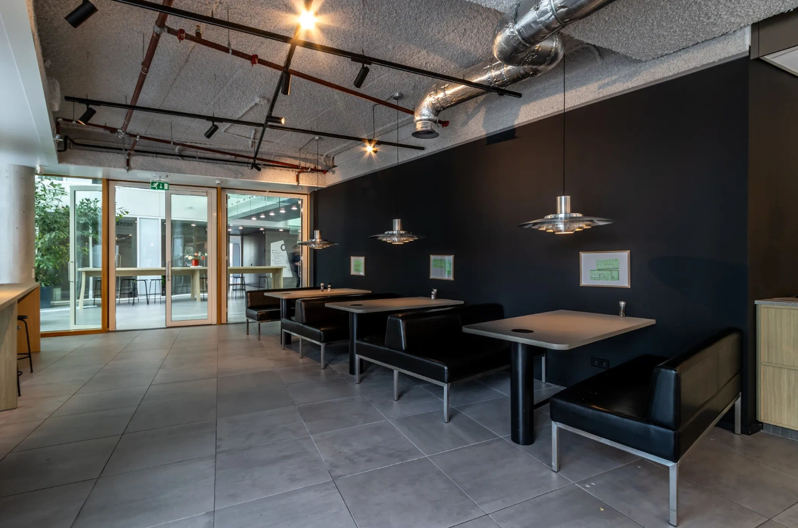 Modern seating area with black booth benches and pendant lighting at Pedro de Medinalaan.