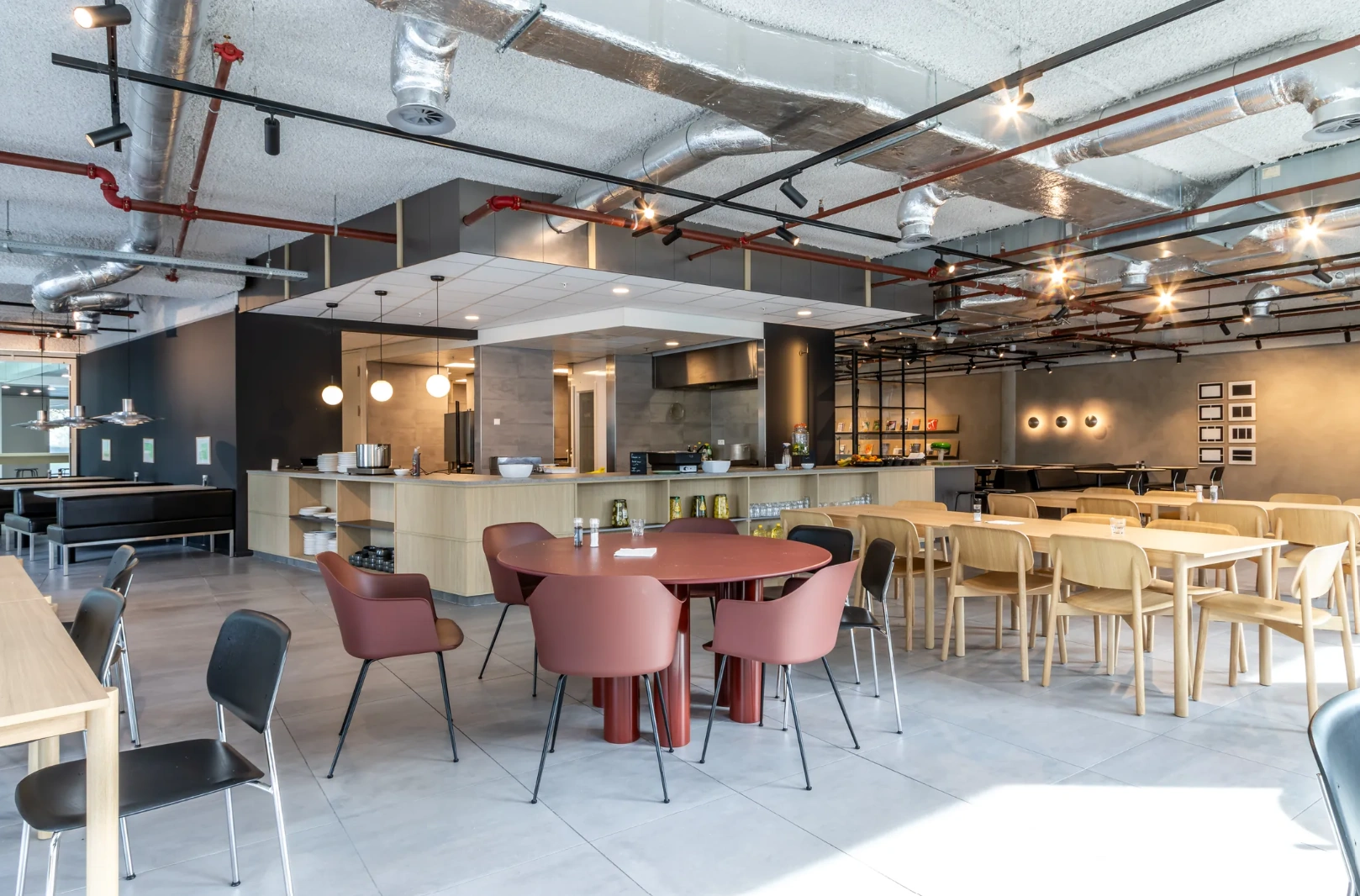 Modern cafeteria interior at Pedro de Medinalaan with mixed seating, sleek furnishings, and an open kitchen area.