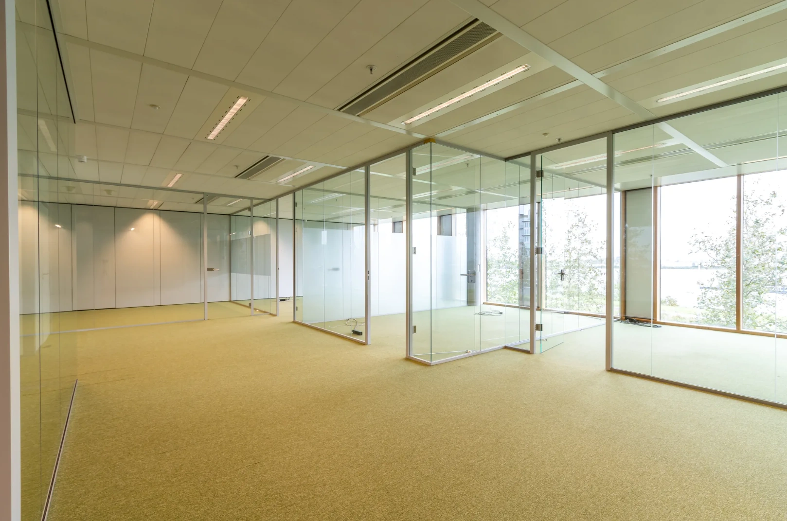 Modern empty office space on Pedro de Medinalaan with glass walls and large windows.