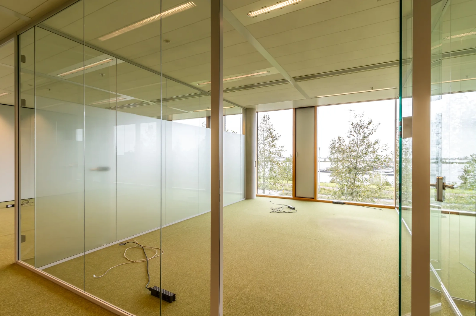 Empty office space with glass walls and large windows overlooking Pedro de Medinalaan.