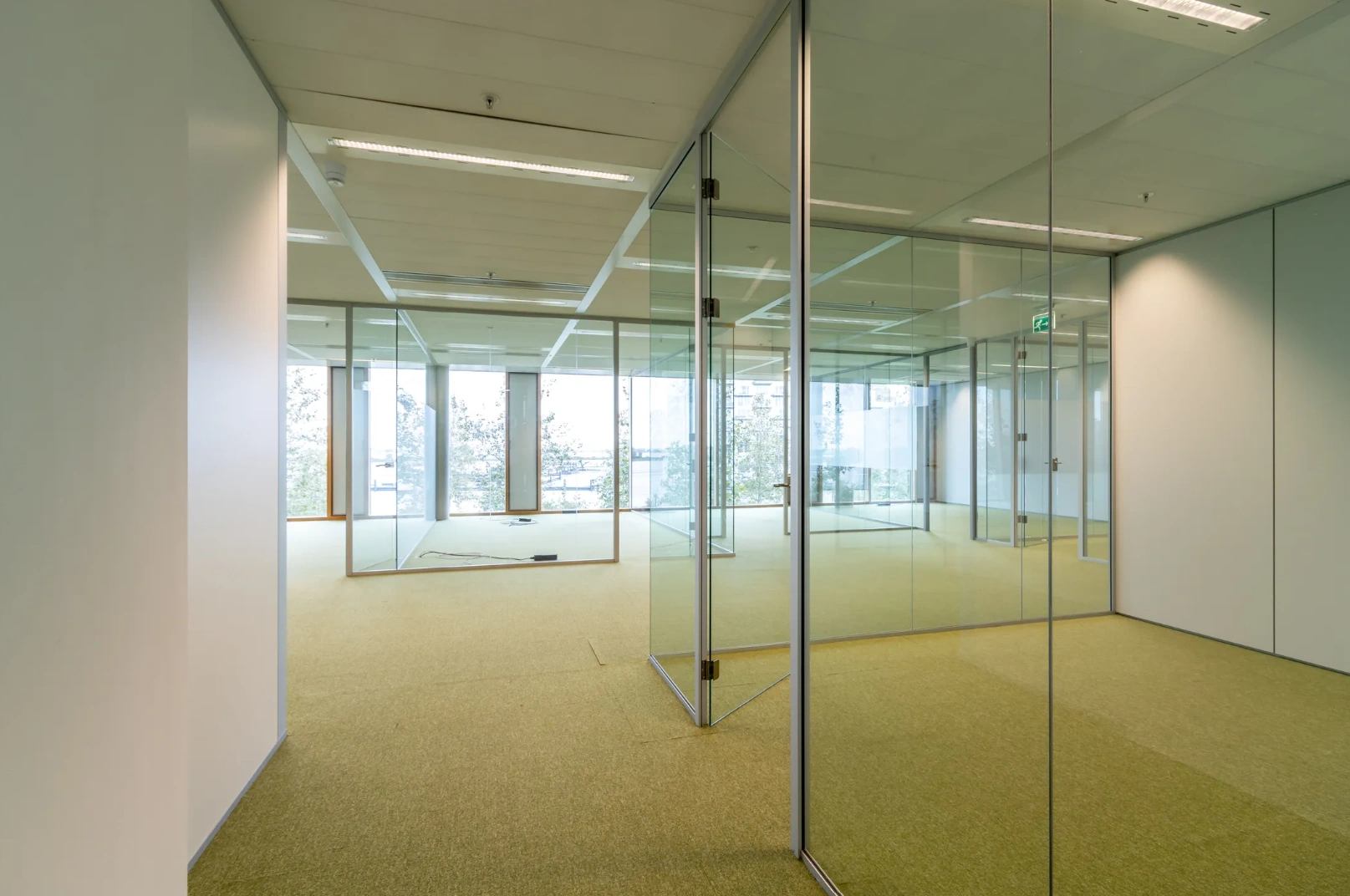 Modern empty office space with glass walls and green carpet at Pedro de Medinalaan.