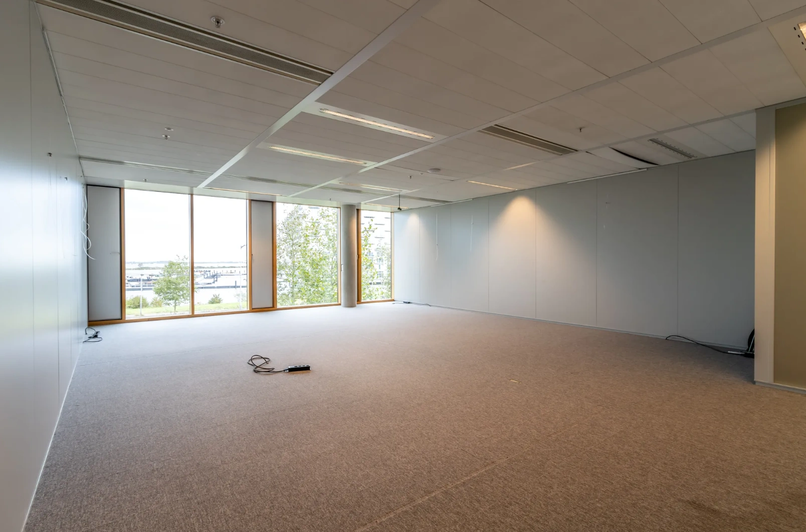 Empty office space on Pedro de Medinalaan with large windows and carpeted flooring.