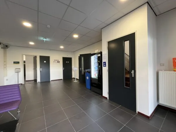 Modern hallway at Archimedesbaan with vending machines, restrooms, and access to a staircase.