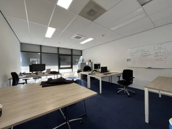 Modern office space on Archimedesbaan with several desks, computer monitors, and a whiteboard with notes.