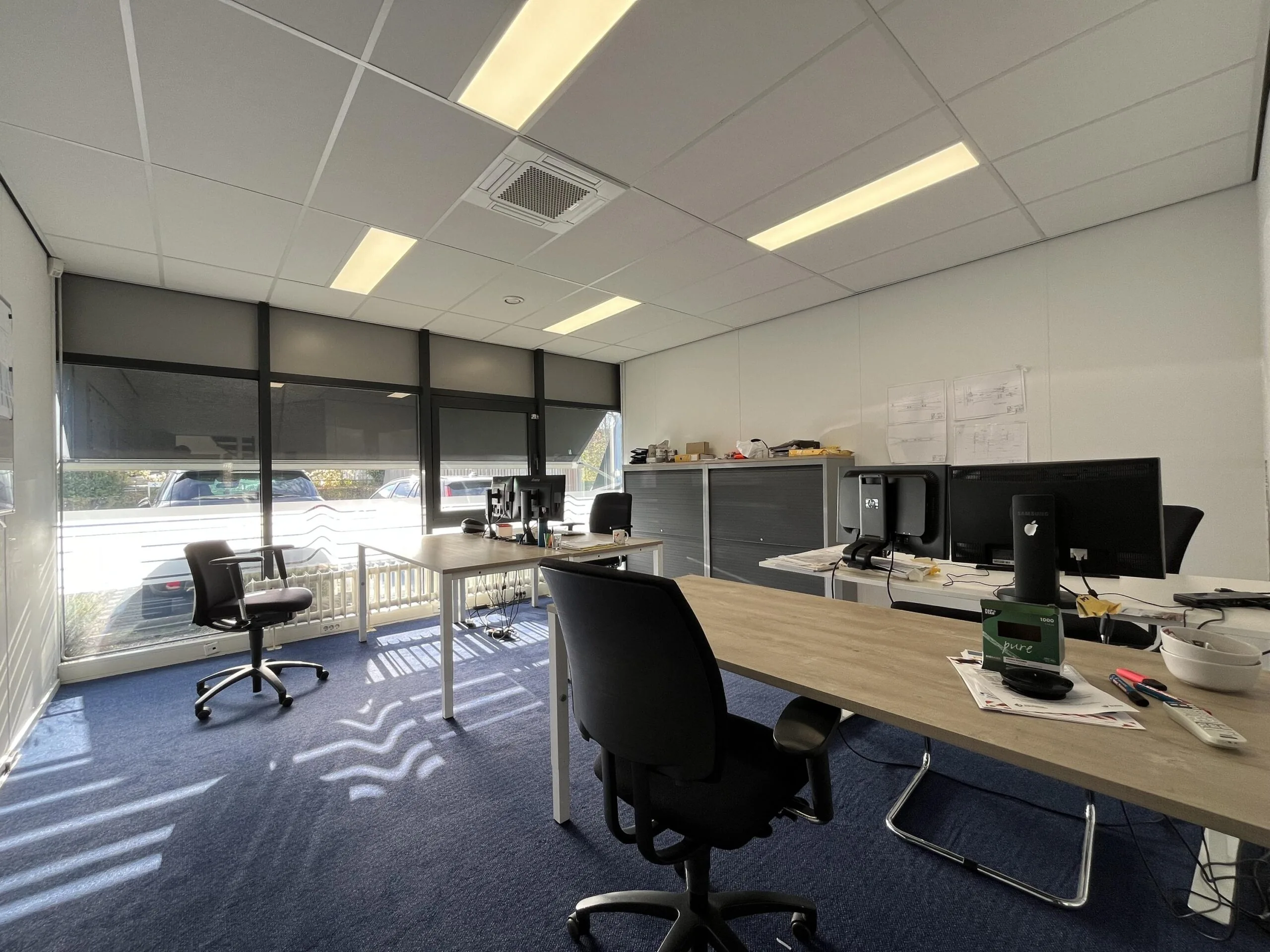 Modern office space on Archimedesbaan with multiple desks, computers, and natural light from large windows.