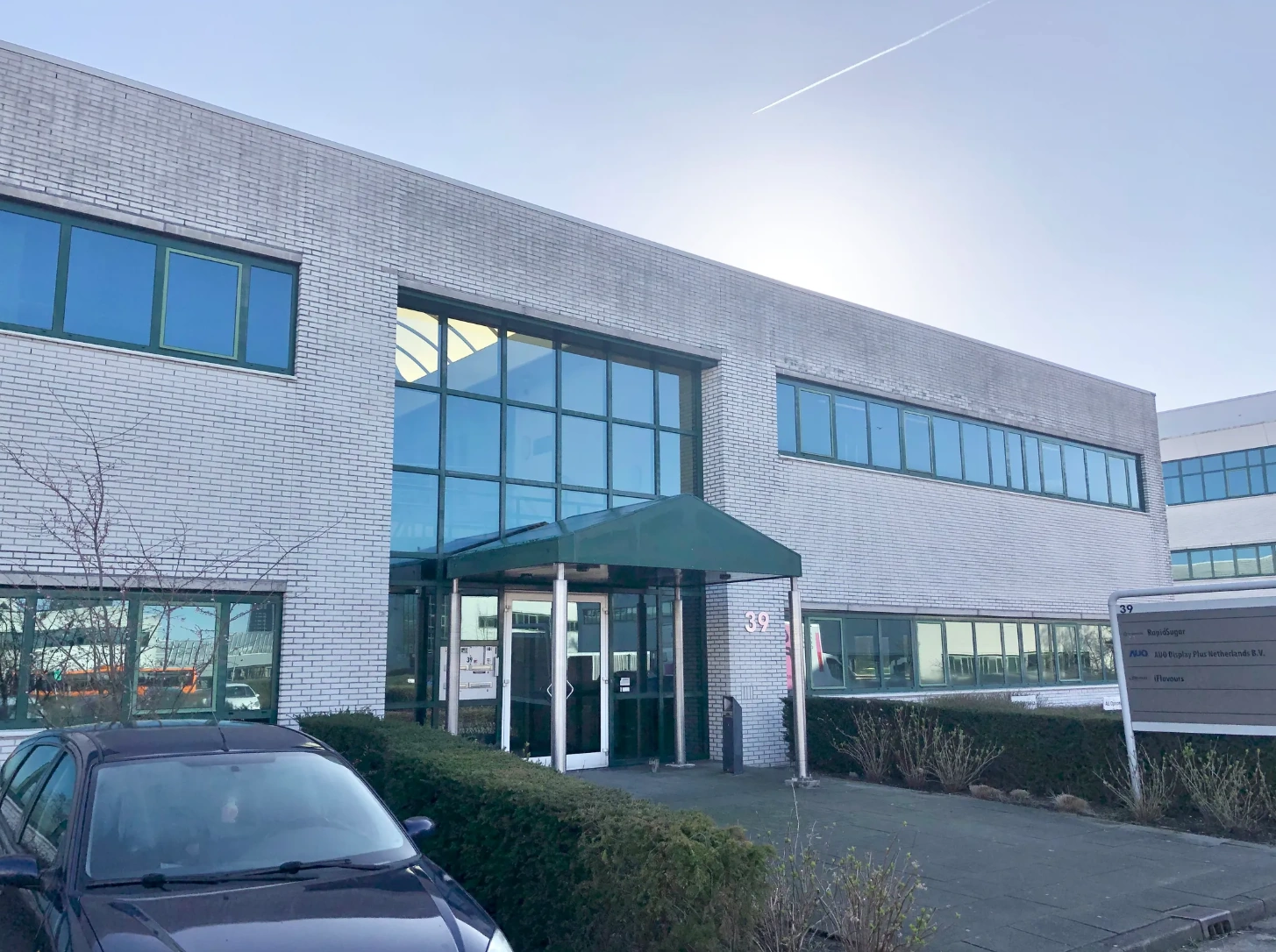 Modern office building at Zekeringstraat 39 with large glass windows and a green entrance canopy.