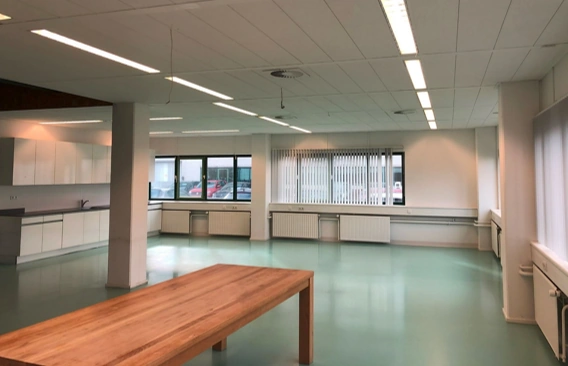 Modern, empty office space on Zekeringstraat with a wooden table, large windows, and a built-in kitchenette.