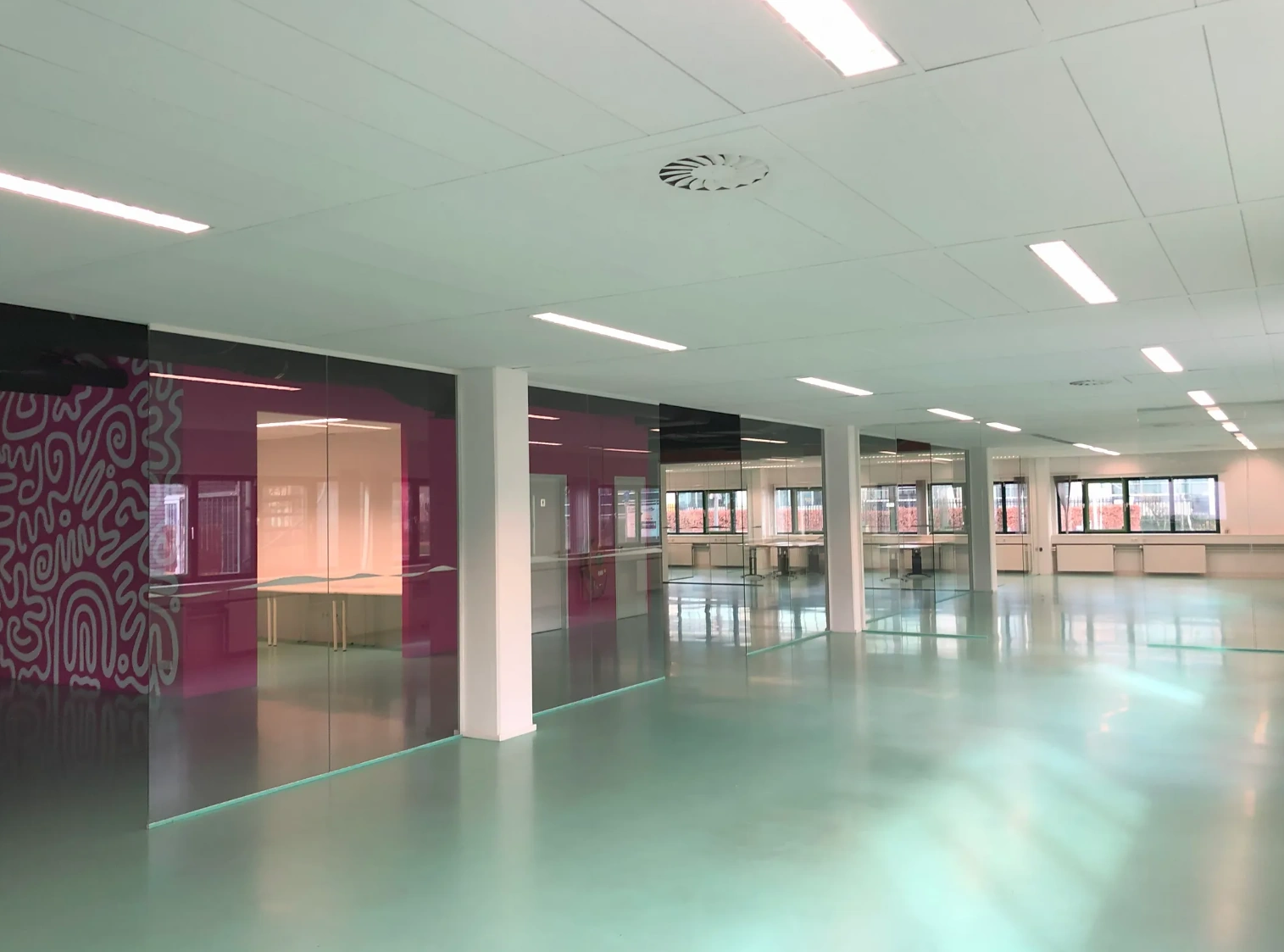 Modern empty office space at Zekeringstraat with glossy floors, glass walls, and colorful accents.