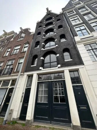 Historic canal house at Herengracht 176 in Amsterdam with a black brick facade and arched windows.