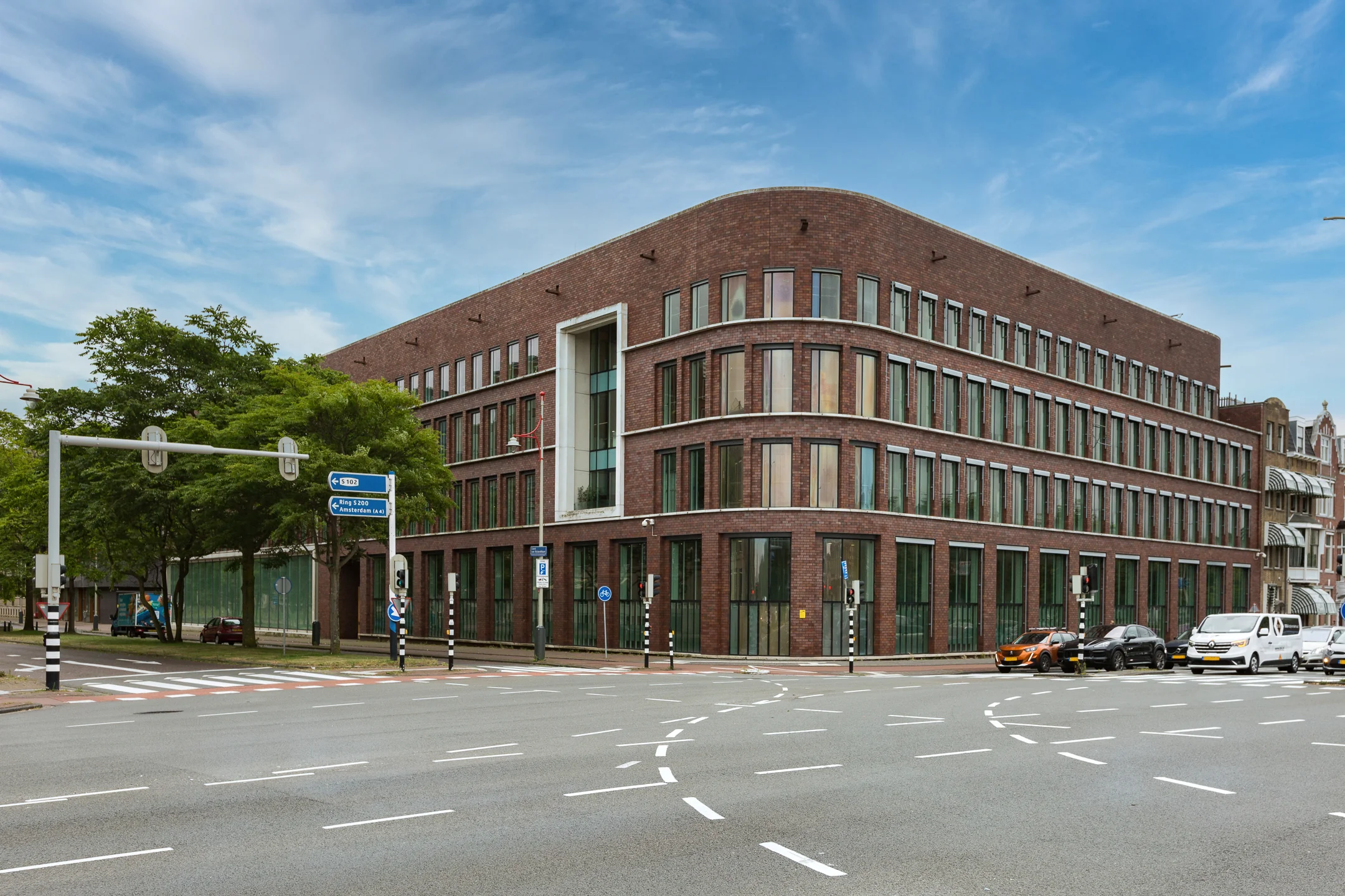 Modern brick office building on Carel van Bylandtlaan at a busy intersection in The Hague.