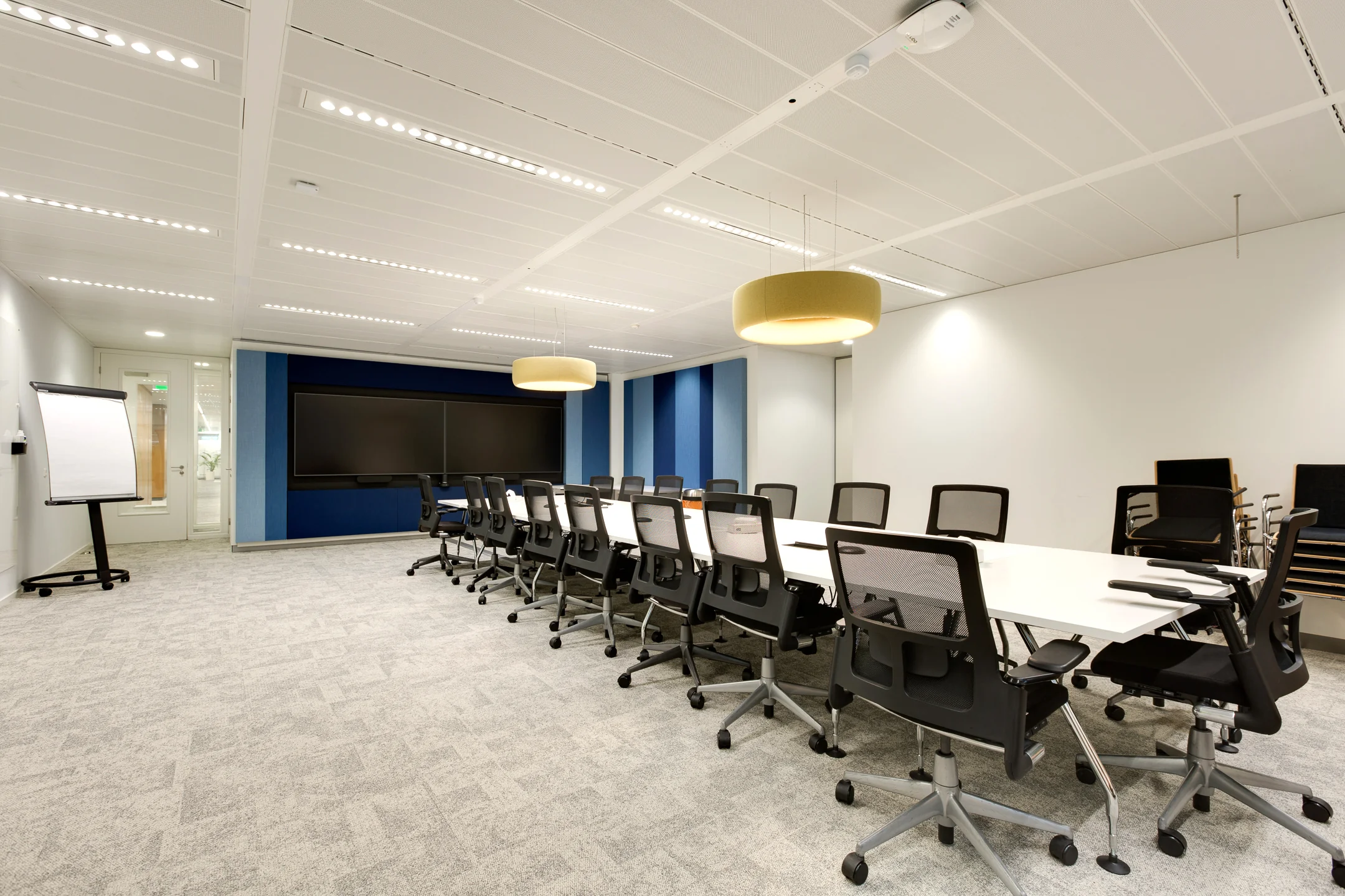 Modern conference room on Carel van Bylandtlaan with a long table, office chairs, large screen, and flip chart.