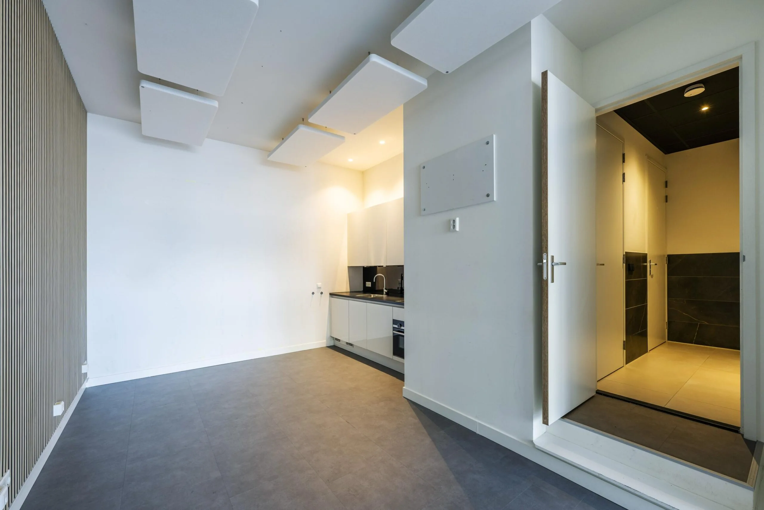 Modern studio interior on James Wattstraat with a small kitchenette, minimalist design, and visible hallway leading to separate rooms.