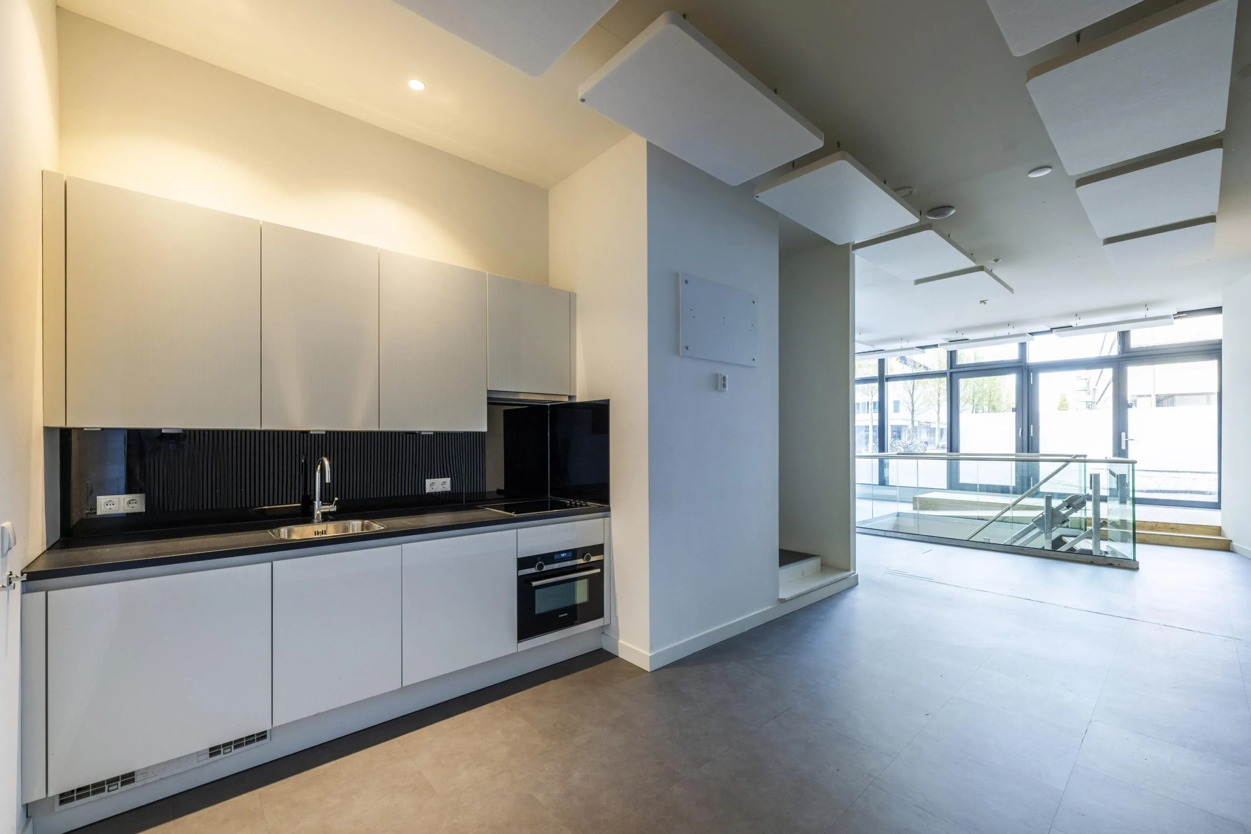 Modern kitchen in a bright open space on James Wattstraat with large windows and a glass staircase.