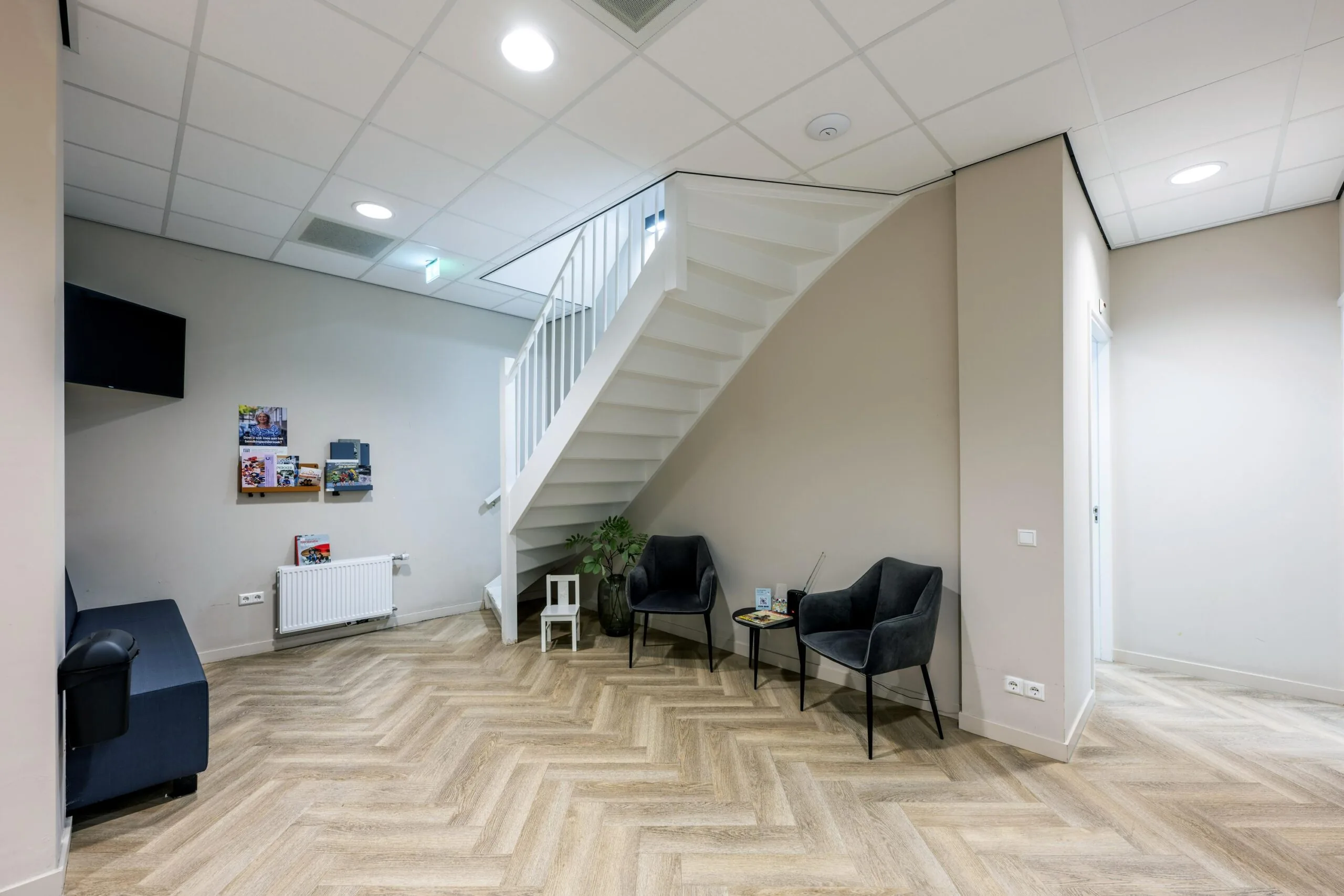 Modern waiting area at Westermarkt with two chairs, a small table, and a white staircase.