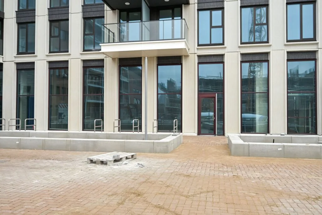 Newly constructed apartment building on Melkwegstraat with large windows, a glass balcony, and an unfinished paved area in front.