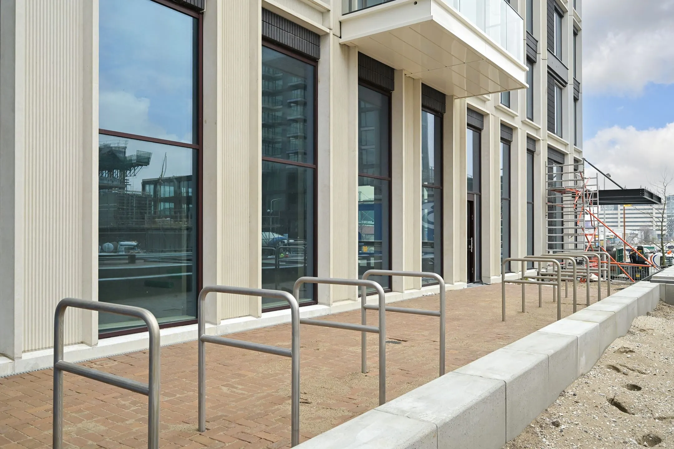 Modern apartment building on Melkwegstraat with large windows, metal bike racks, and a construction scaffold by the entrance.