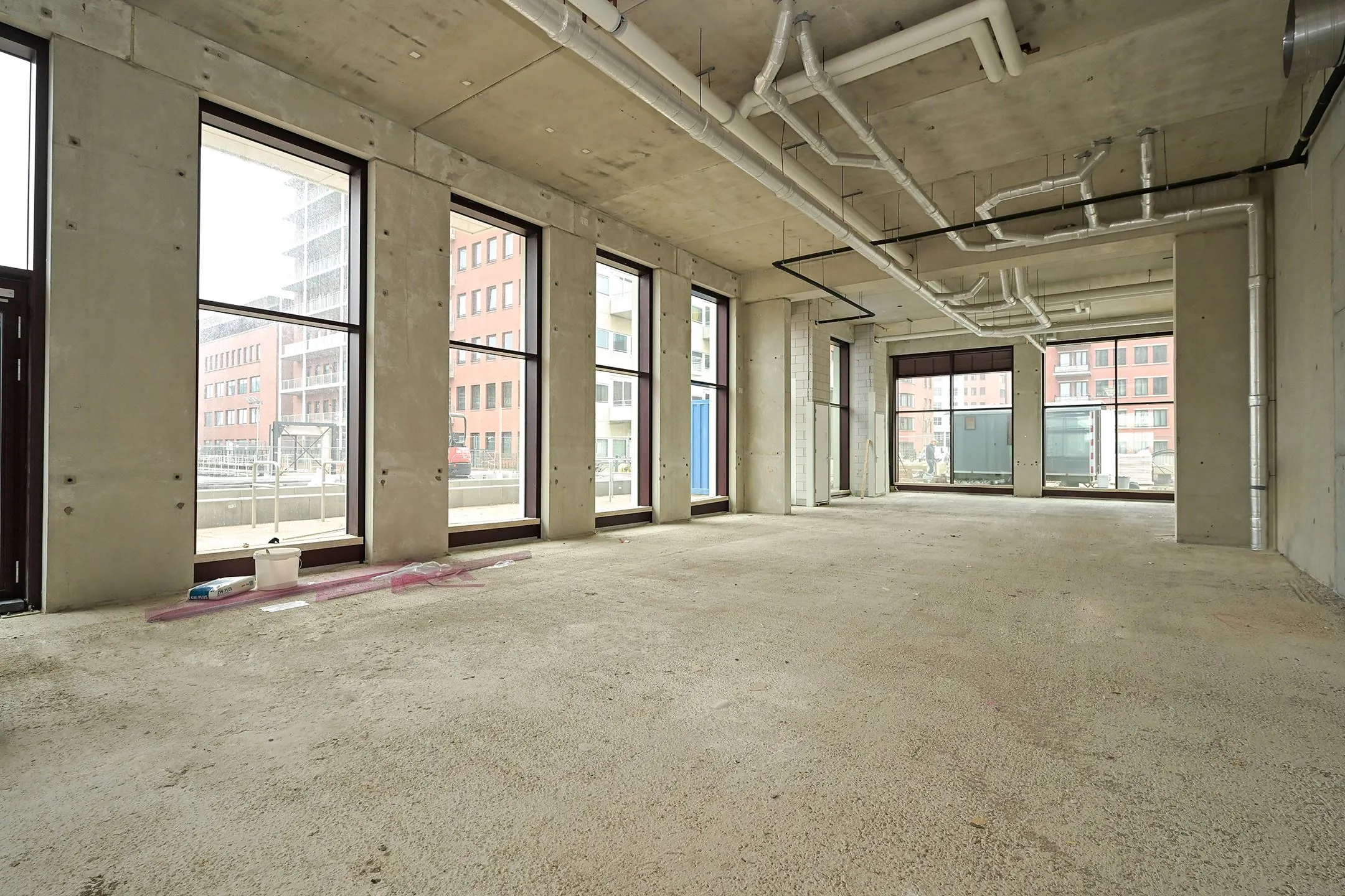 Empty commercial space on Melkwegstraat with unfinished concrete interior and large street-facing windows.