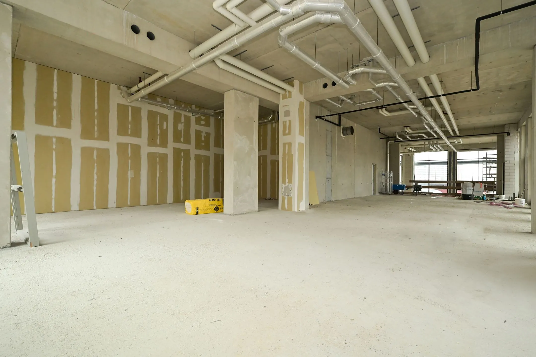Empty commercial space under construction on Melkwegstraat, with visible ductwork, unfinished walls, and construction materials.