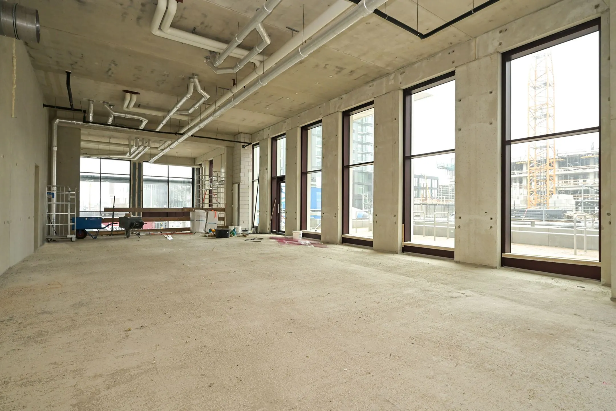 Empty industrial-style interior space under construction on Melkwegstraat with large windows and exposed ceiling pipes.