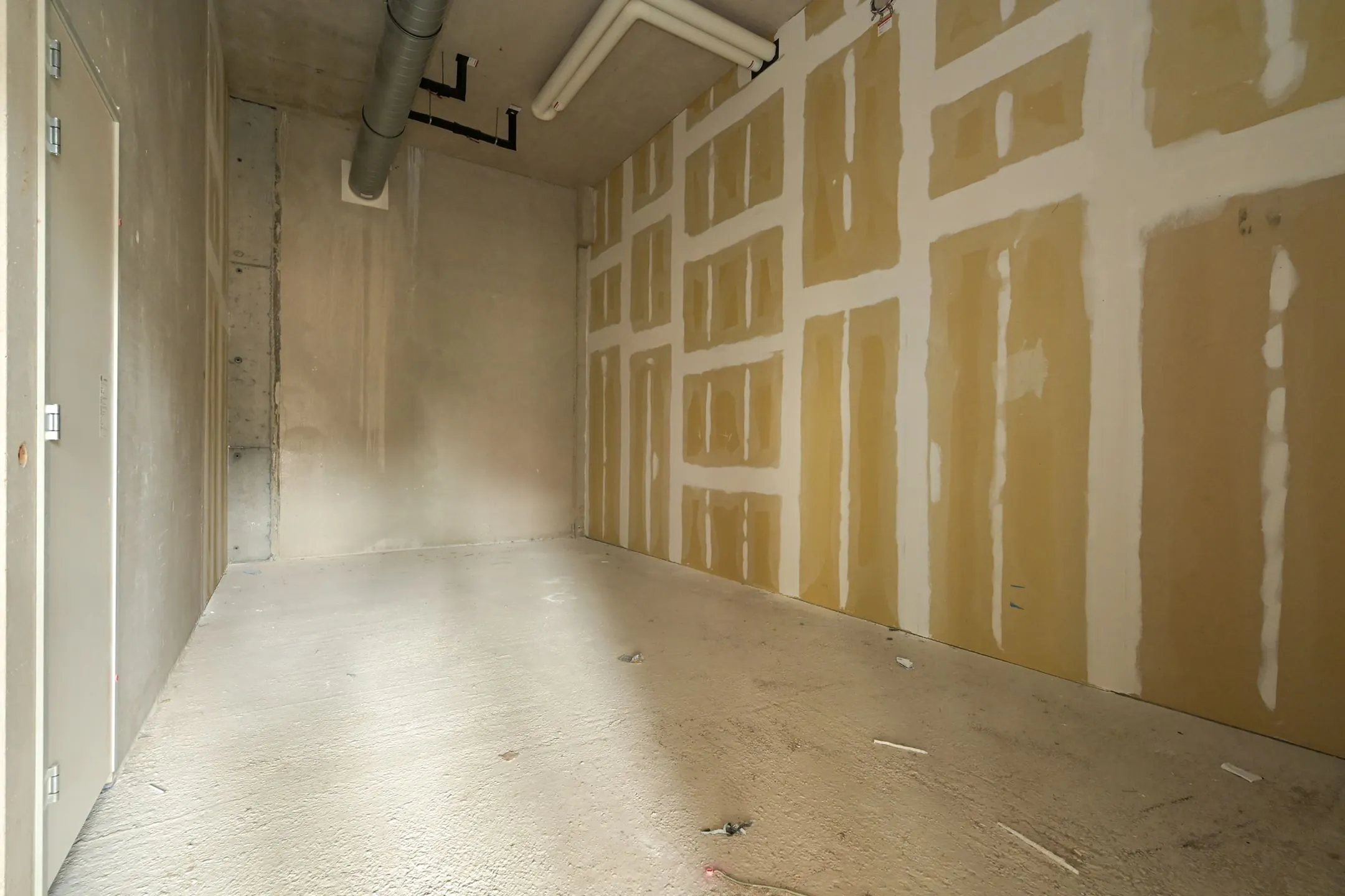 Unfinished utility room with concrete floor, visible ductwork, and partially taped drywall on Melkwegstraat.