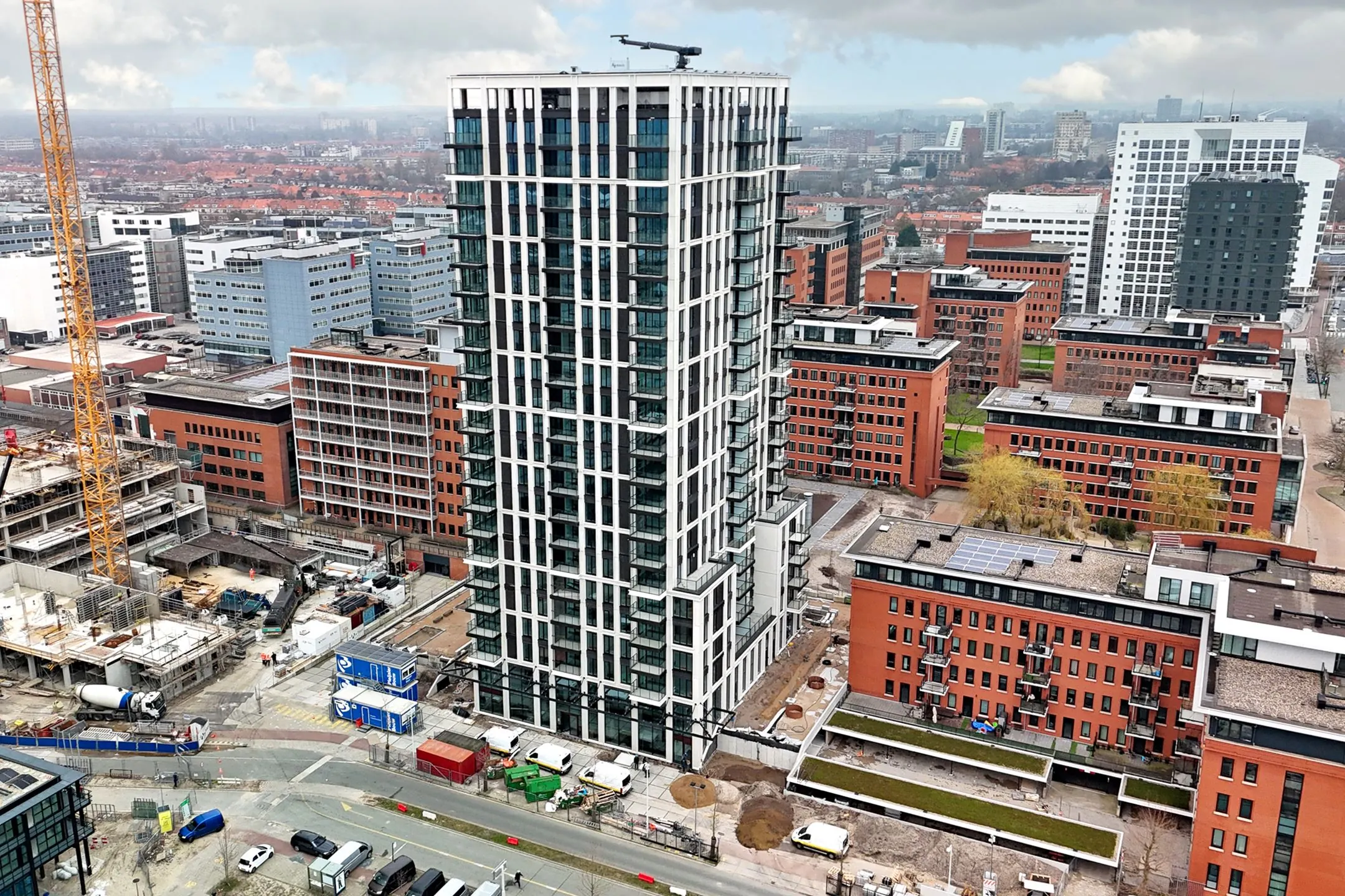 High-rise residential building on Melkwegstraat surrounded by modern apartment complexes and construction activity in an urban setting.