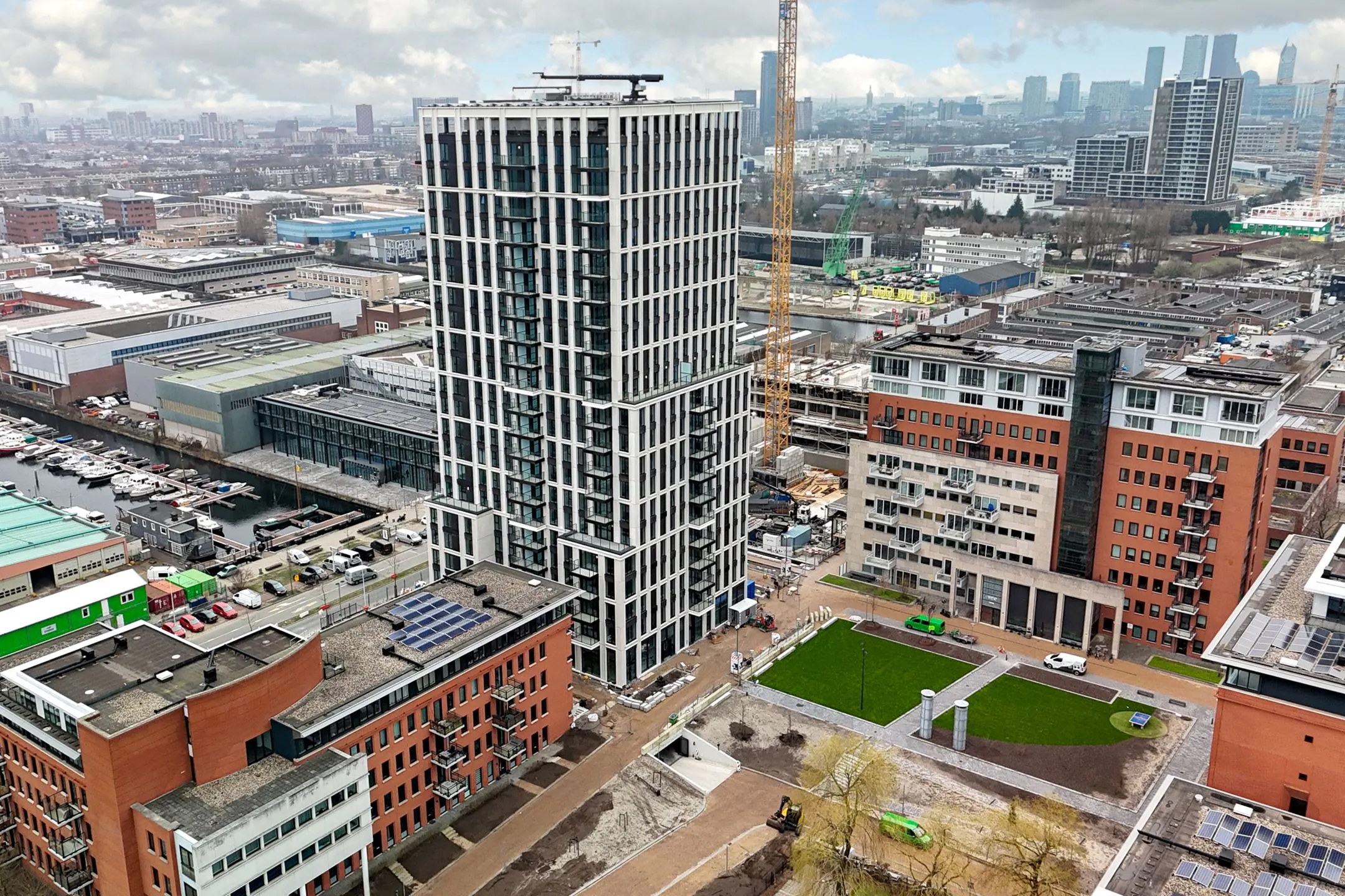 Aerial view of a modern high-rise building on Melkwegstraat surrounded by office and residential buildings in an urban area.