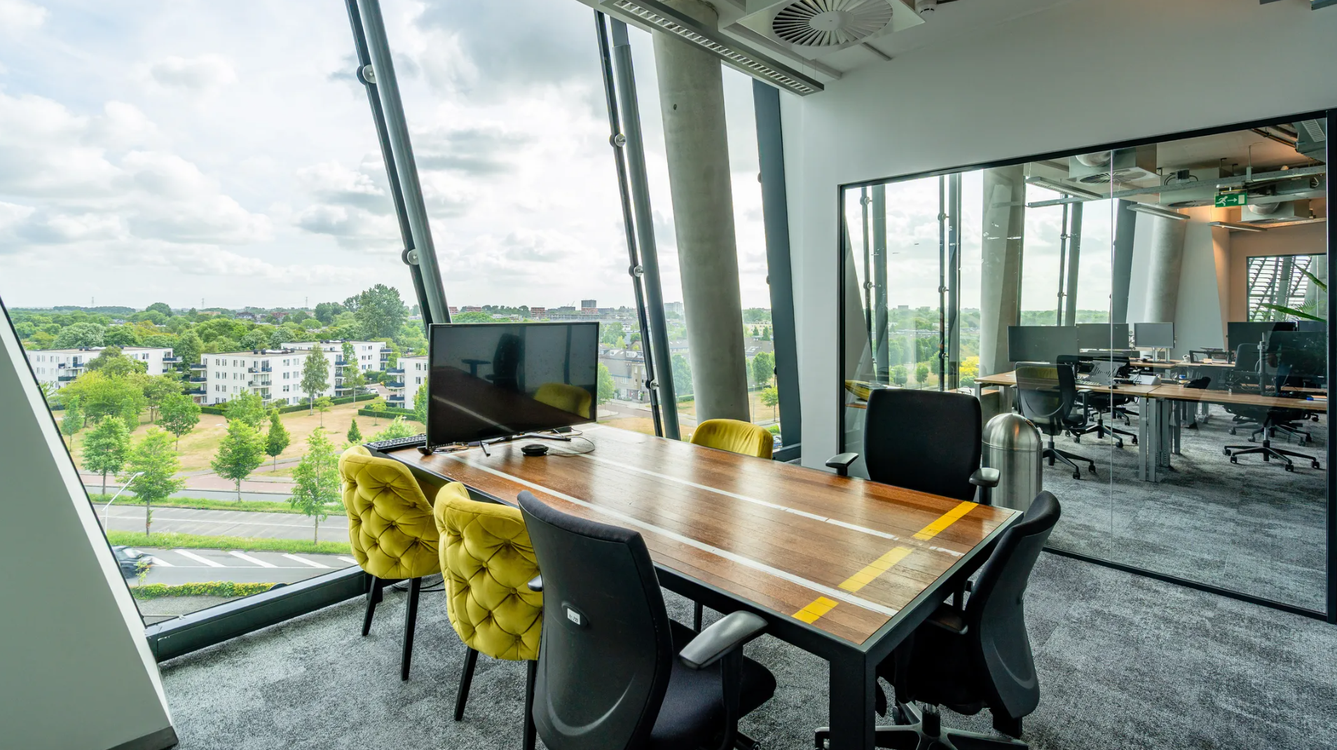 Modern meeting room at TT Vasumweg with large windows overlooking a green residential area.