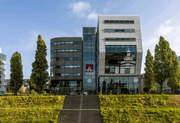Modern office building of the IBFD at Rietlandpark in Amsterdam, viewed from the front with wide steps and trees in the foreground.