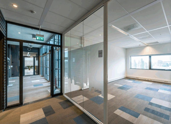 Modern office hallway with glass-walled meeting room and city skyline decals at Rietlandpark.