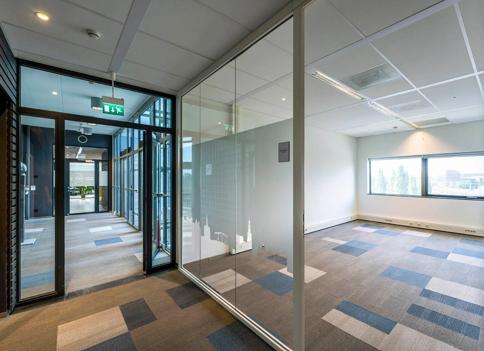 Modern office hallway with glass-walled meeting room and city skyline decals at Rietlandpark.