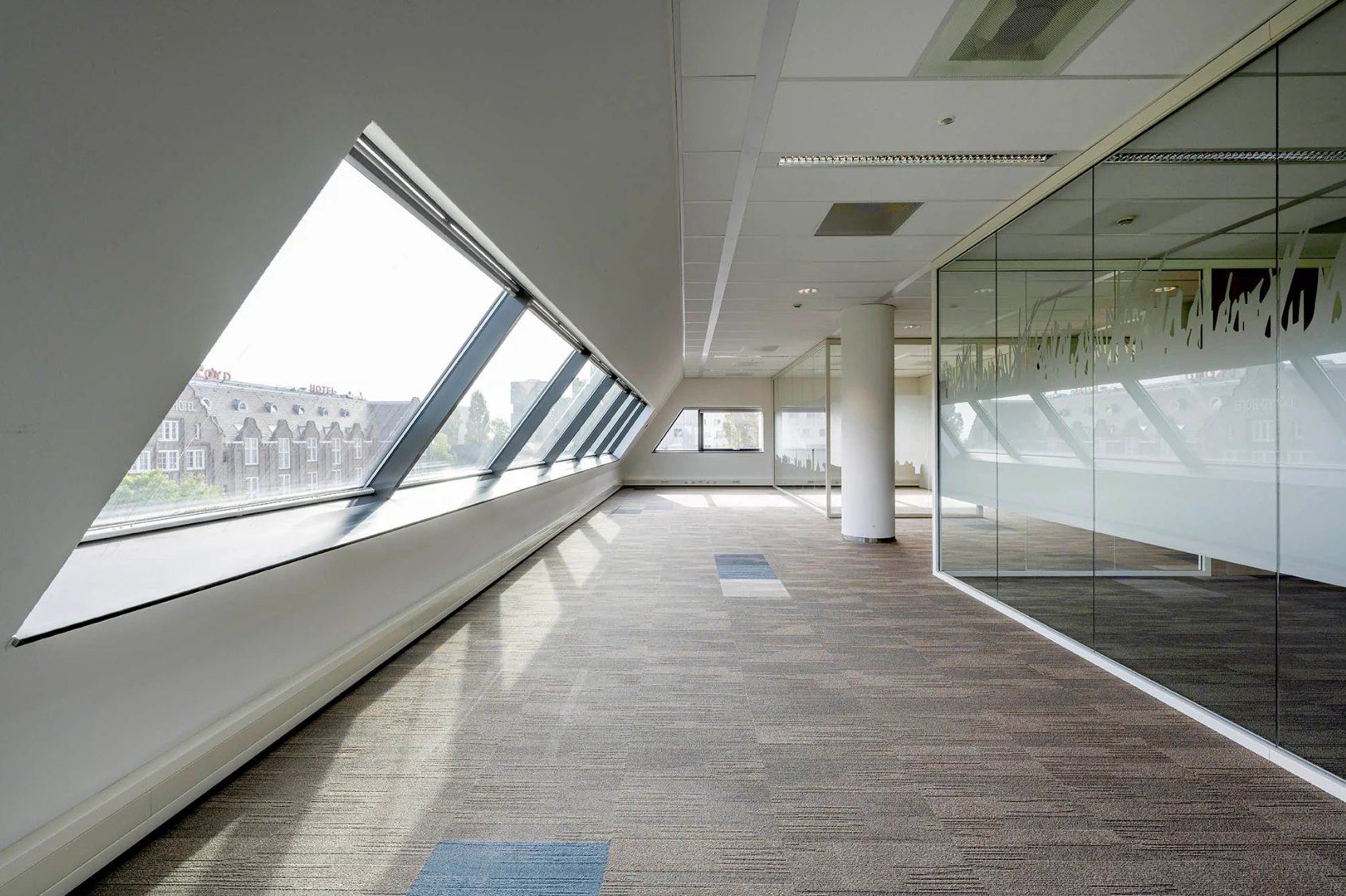 Modern office space in Rietlandpark with slanted windows and glass partitions.