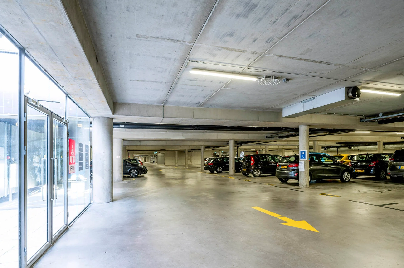 Underground parking garage at Rietlandpark with parked cars and directional arrows on the floor.