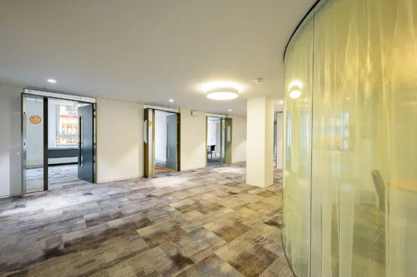 Een moderne kantoorruimte met openstaande glazen deuren en een gebogen glazen wand.