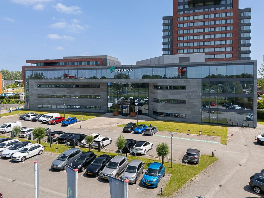 Modern office building of Equans on Laan van Barcelona with a parking lot in front.