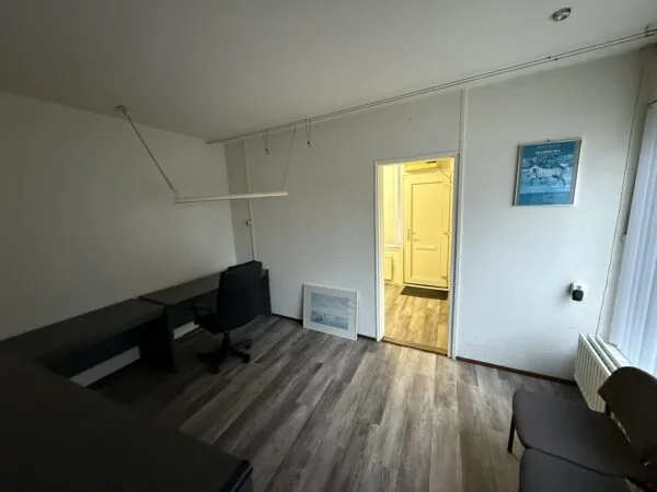 Simple office room on Katendrechtse Lagedijk with a desk, chair, and framed picture on the wall.