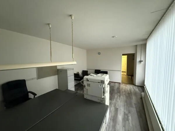 Office space on Katendrechtse Lagedijk with desks, chairs, a printer, and vertical blinds.