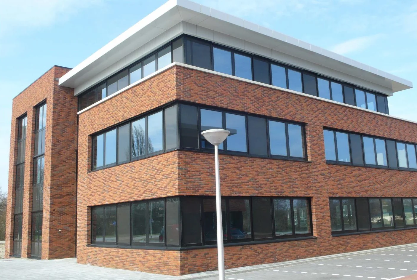 Modern three-story office building with red brick facade located on Veteranenlaan.