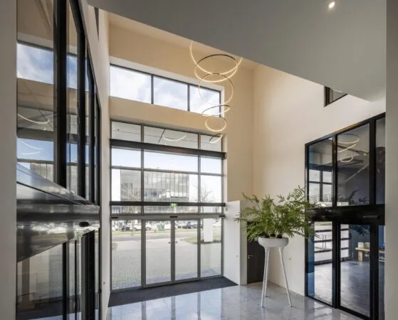 Modern office entrance at Dynamostraat with large windows, marble floors, and a spiral LED chandelier.