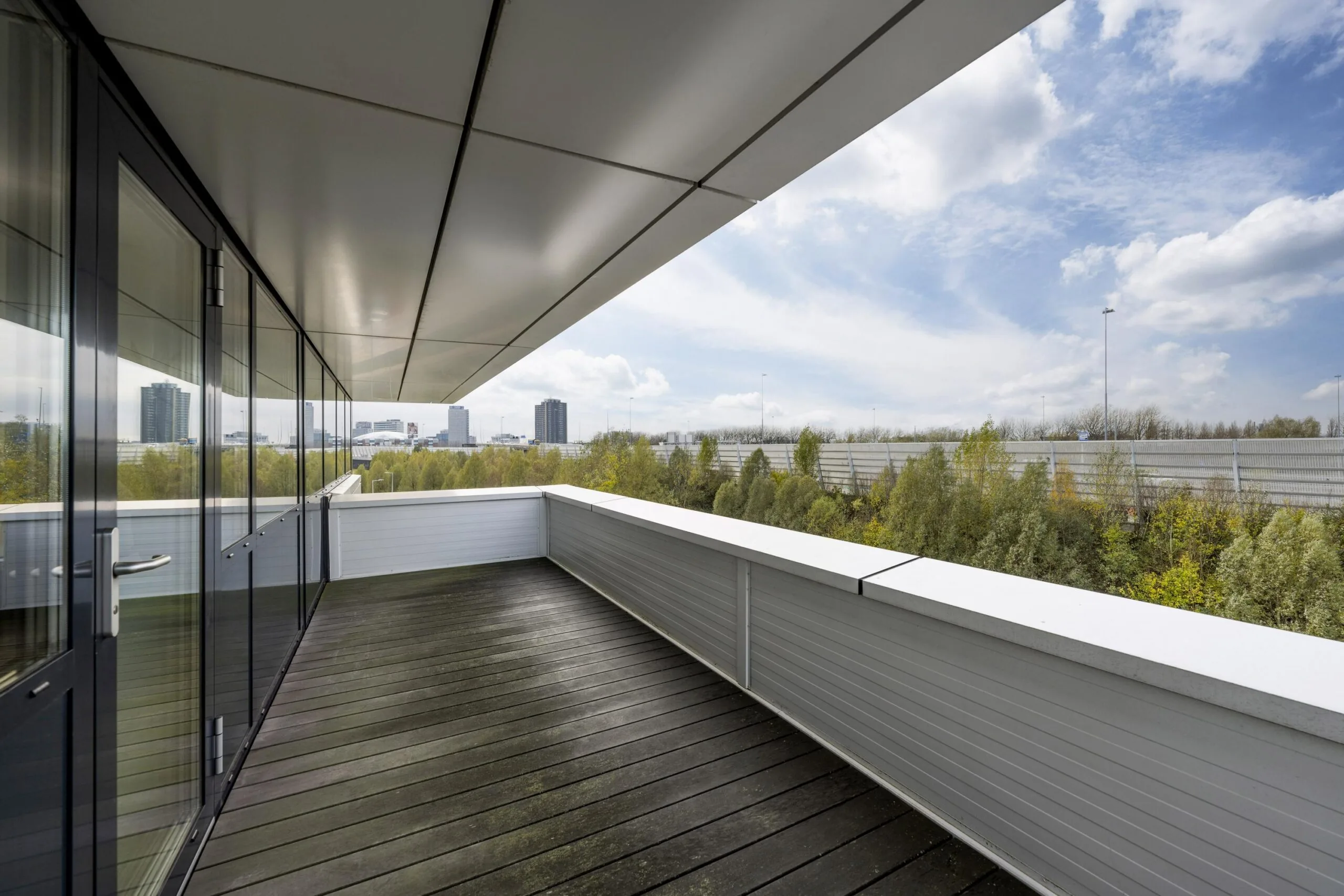 Spacious modern balcony on Dynamostraat with city skyline and greenery in the background.
