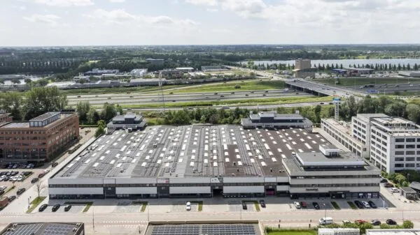 Aerial view of a large commercial building on Zonnebaan street with solar panels on the roof, located next to a busy highway.