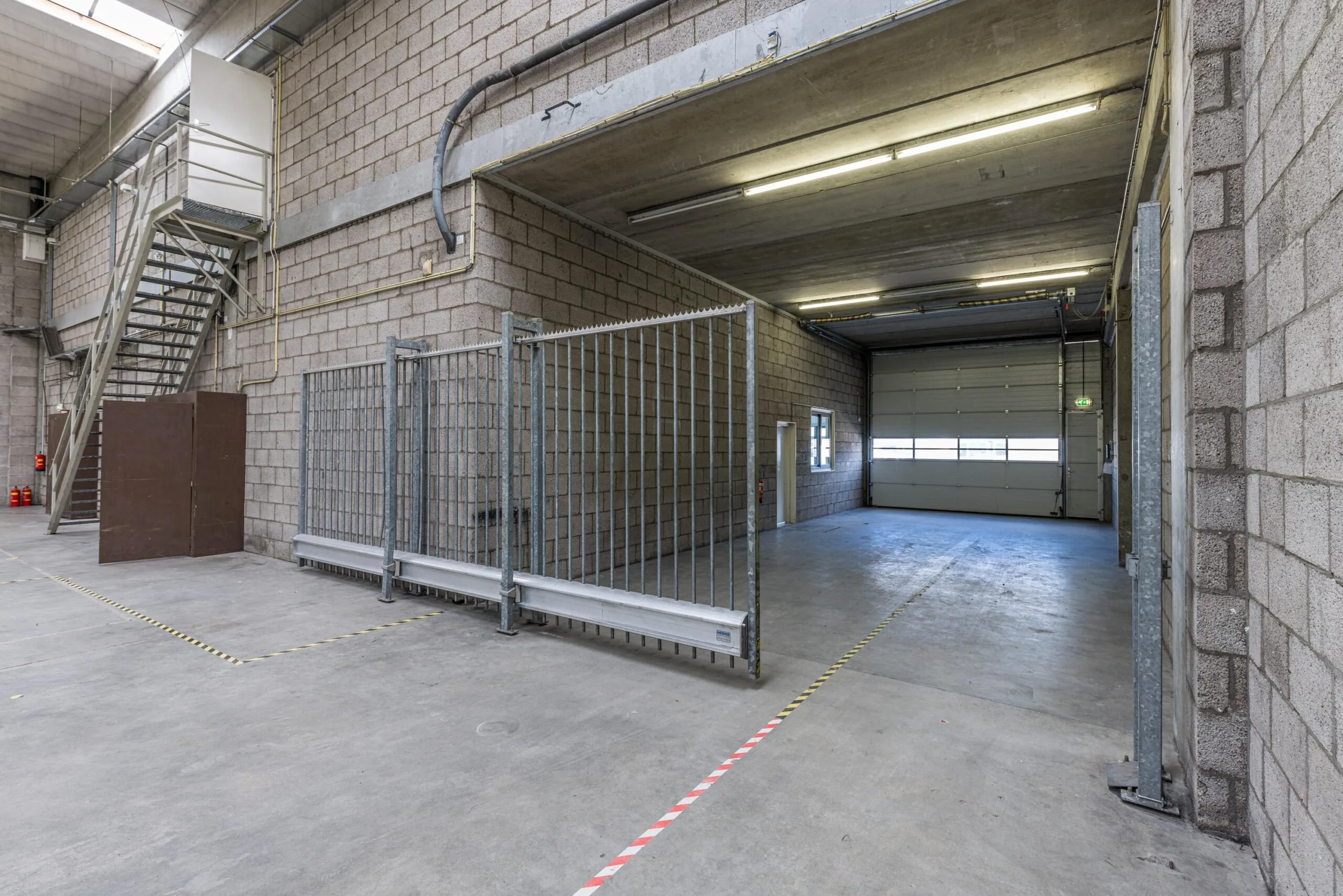 Industrial warehouse unit at Zonnebaan with high ceiling, roller shutter door, and metal staircase.