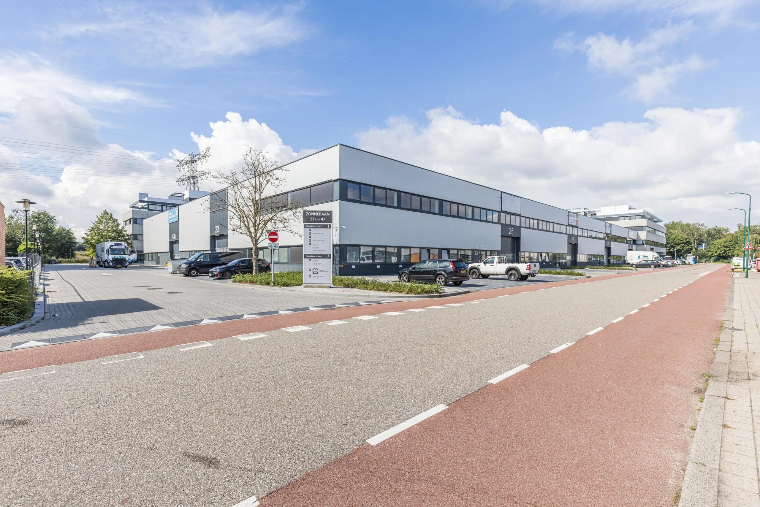 Modern industrial buildings and offices on Zonnebaan street with parked cars and a clear blue sky.