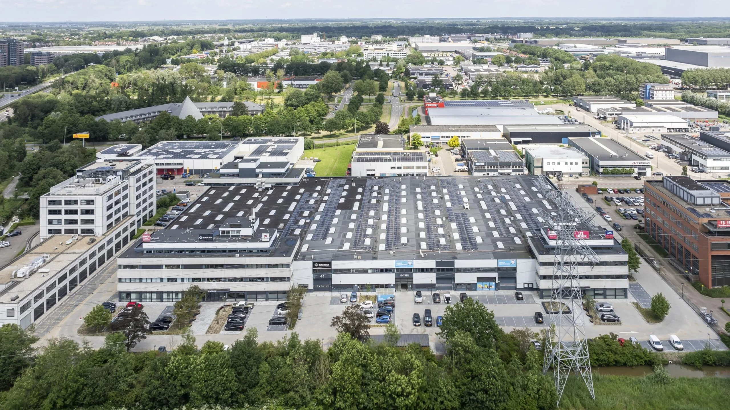 Aerial view of a large industrial complex on Zonnebaan with solar panels on the rooftops and surrounding office buildings.