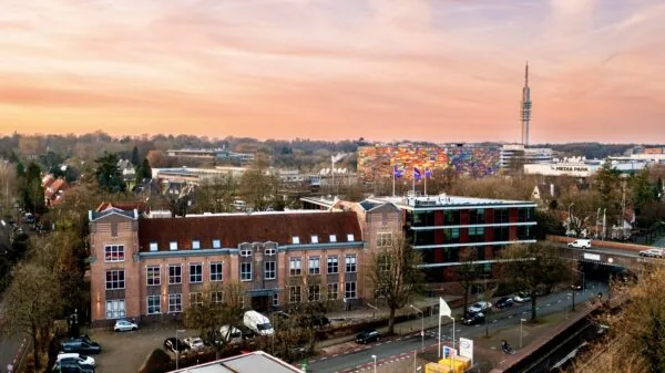 Aerial view of the Lage Naarderweg in Hilversum with Media Park, a colorful building facade, and the transmission tower at sunset.