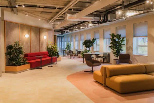 Modern office lounge on Hullenbergweg with colorful seating, indoor plants, and large windows.