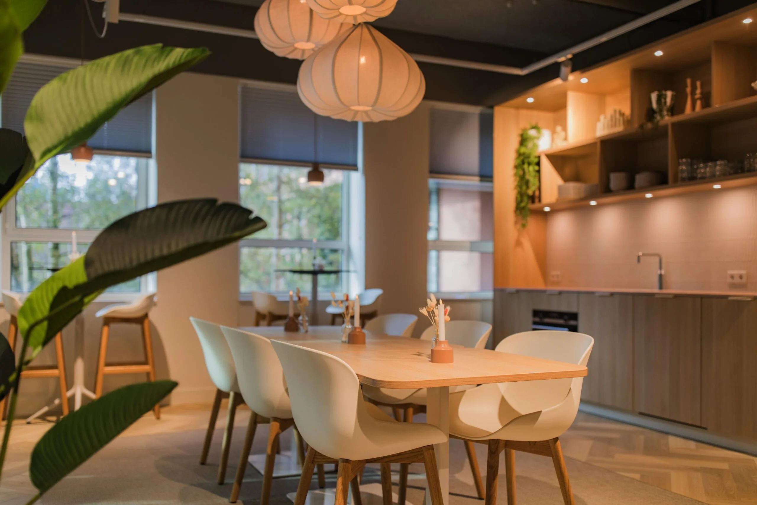 Modern office kitchen and dining area on Hullenbergweg with wooden furnishings, pendant lighting, and minimalist decor.