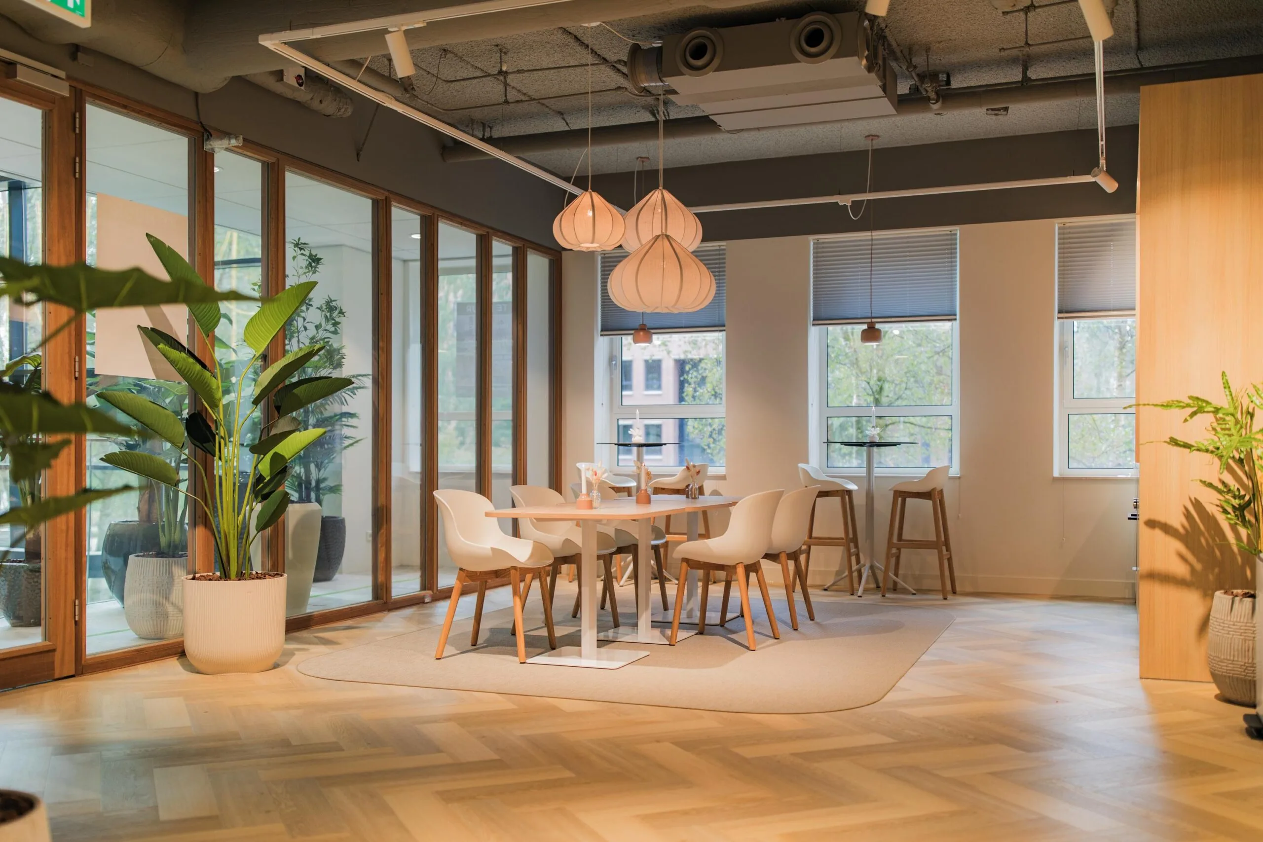Modern office lounge with wooden flooring, stylish pendant lights, and a seating area at Hullenbergweg.