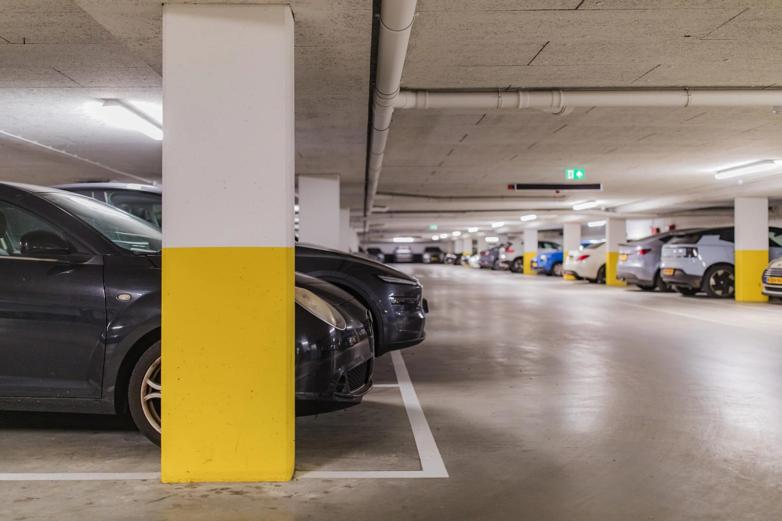 Underground parking garage on Hullenbergweg with parked cars and yellow-marked support columns.