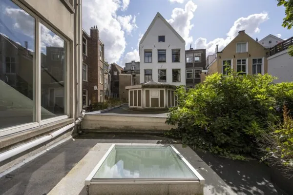 Uitzicht op een binnentuin en omliggende gevels aan de Nieuwe Spiegelstraat met een lichtkoepel op het platte dak.
